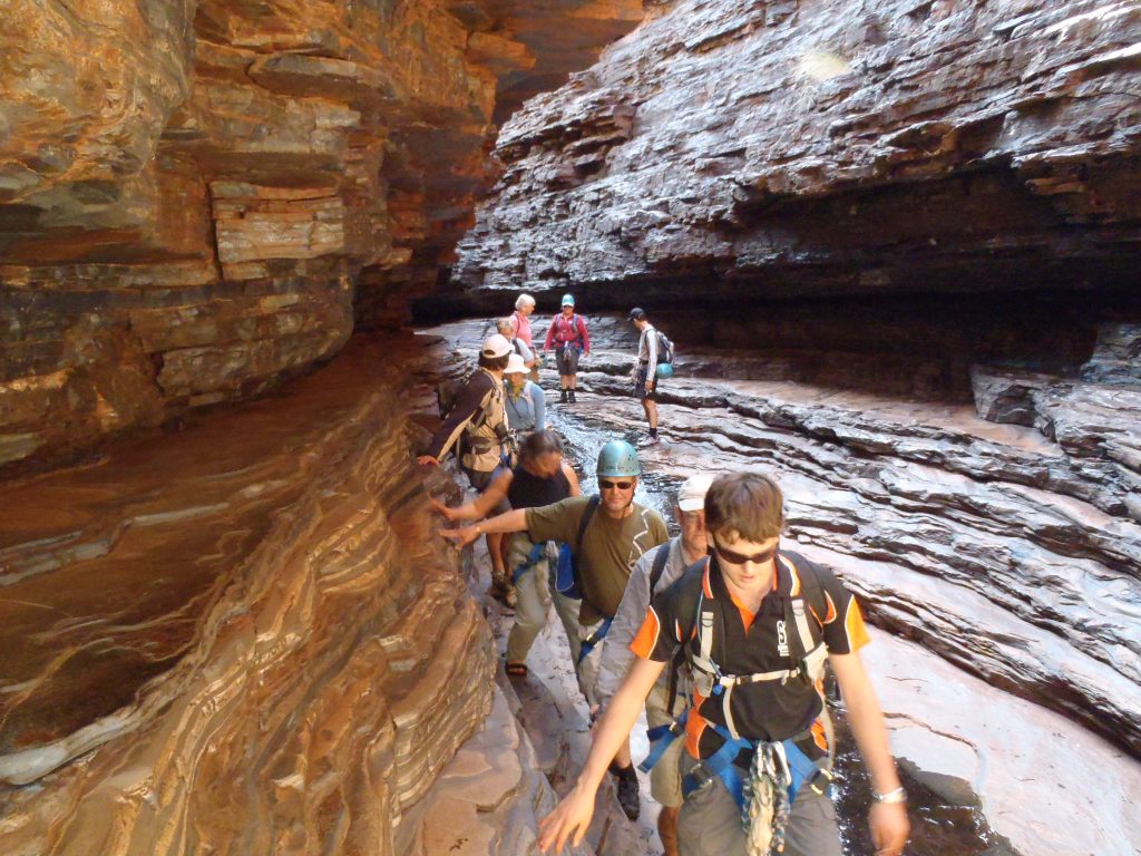A group of people with climbing equipment walking through a gorge in Karijini National Parke